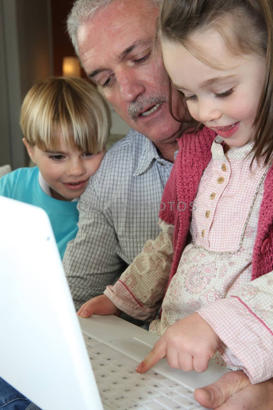 grandfather and grandchildren with laptop by phovoir