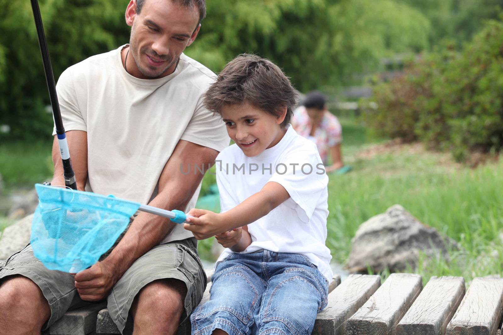 father and son enjoying fishing party by riverside