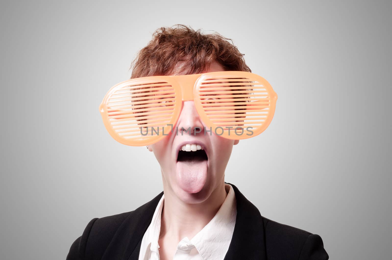 businesswoman with big funny eyeglasses and tongue out on gray background