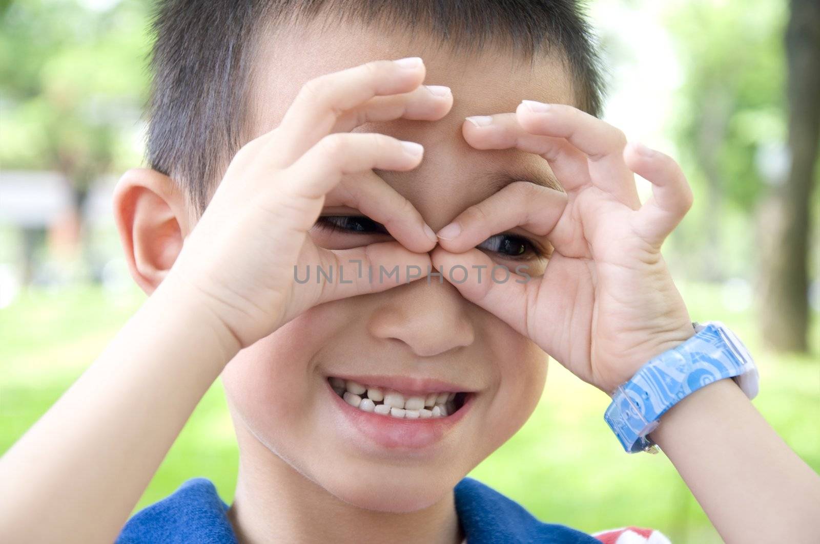 Cute boy watch right with his hand in the park