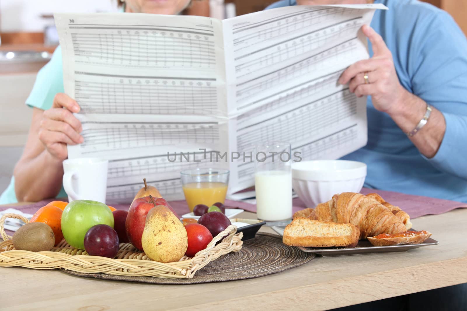 Couple reading newspaper during breakfast by phovoir