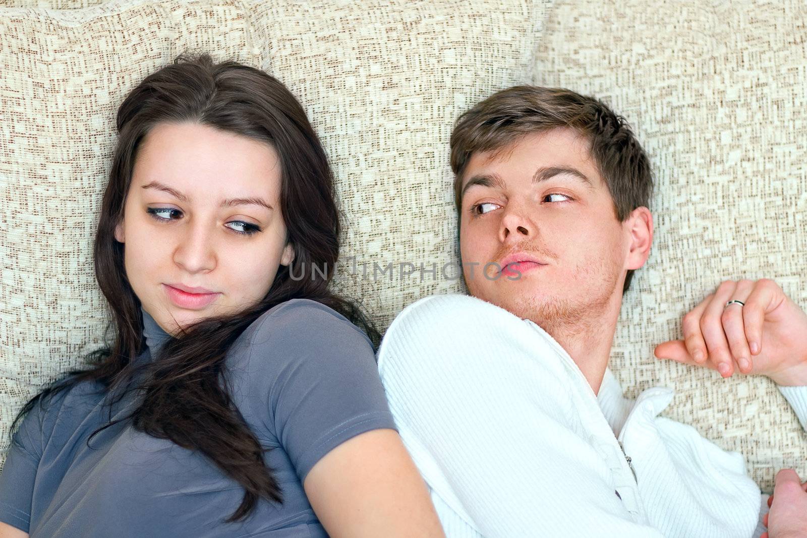 young boy and girl look at each other while lying on bed