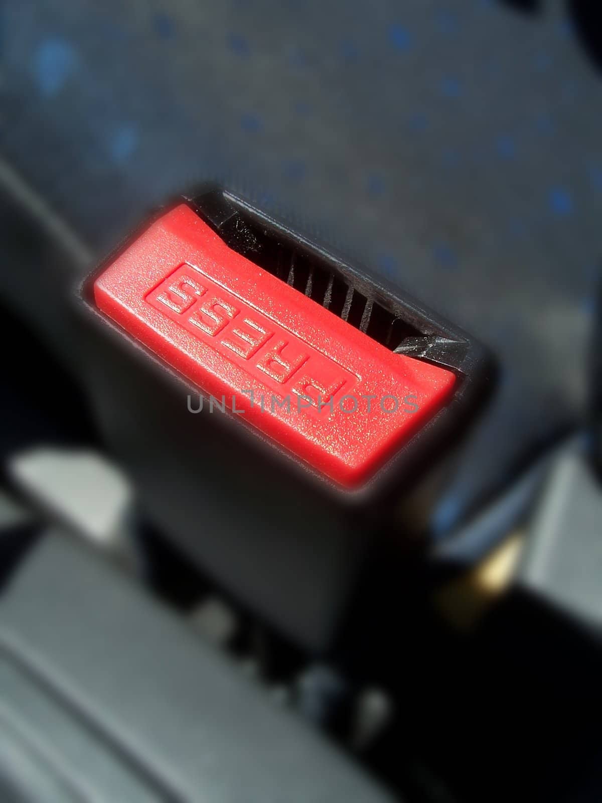 Car seatbelt press button clear and surroundings are blurred, to enhance button.