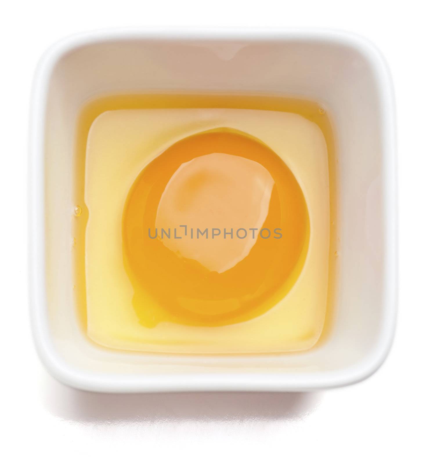 Egg yolk in square cup. Isolated on a white background. 