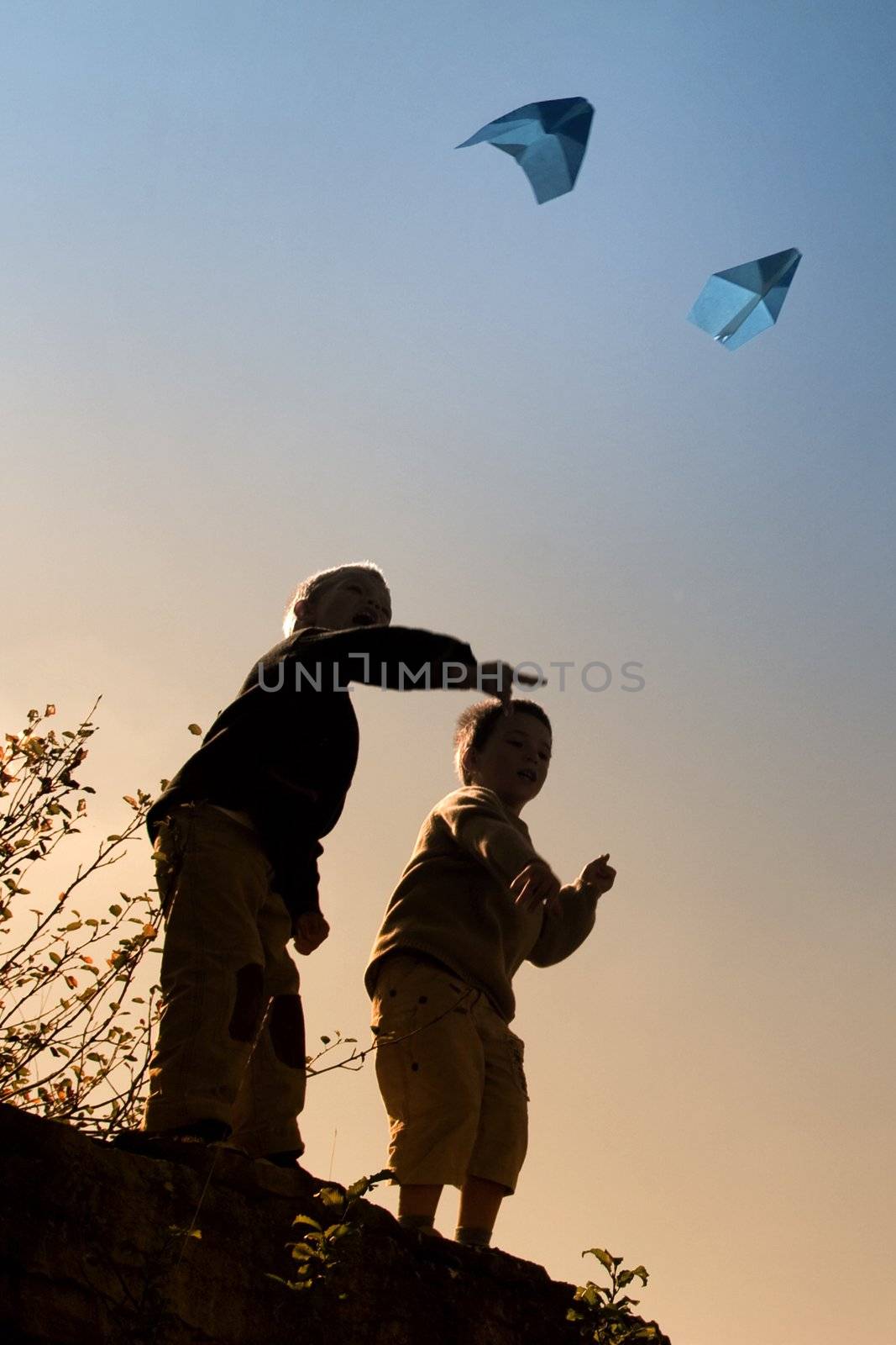 Two children playing with paper airplanes by chrisroll