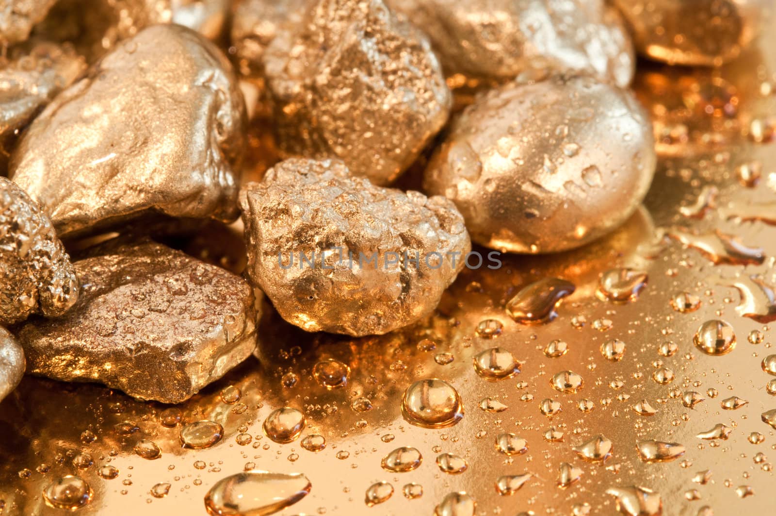 shiny gold nuggets and water drop background. closeup.