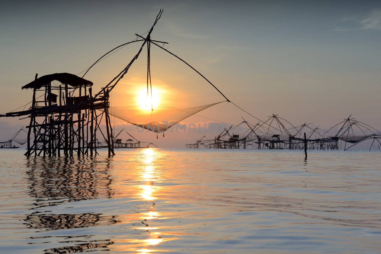 silhouette traditional fishing method using a bamboo square dip net with sunrise background in Patthalung, Thailand