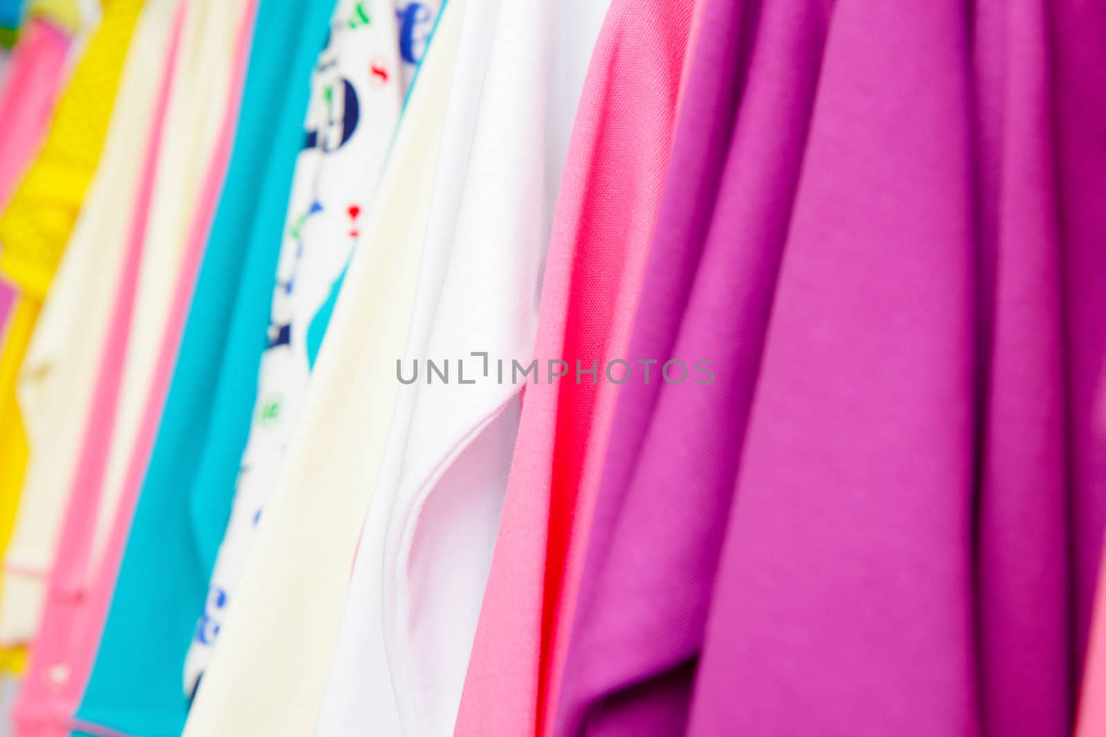 a lot of bright children's clothing on a hanger in the store