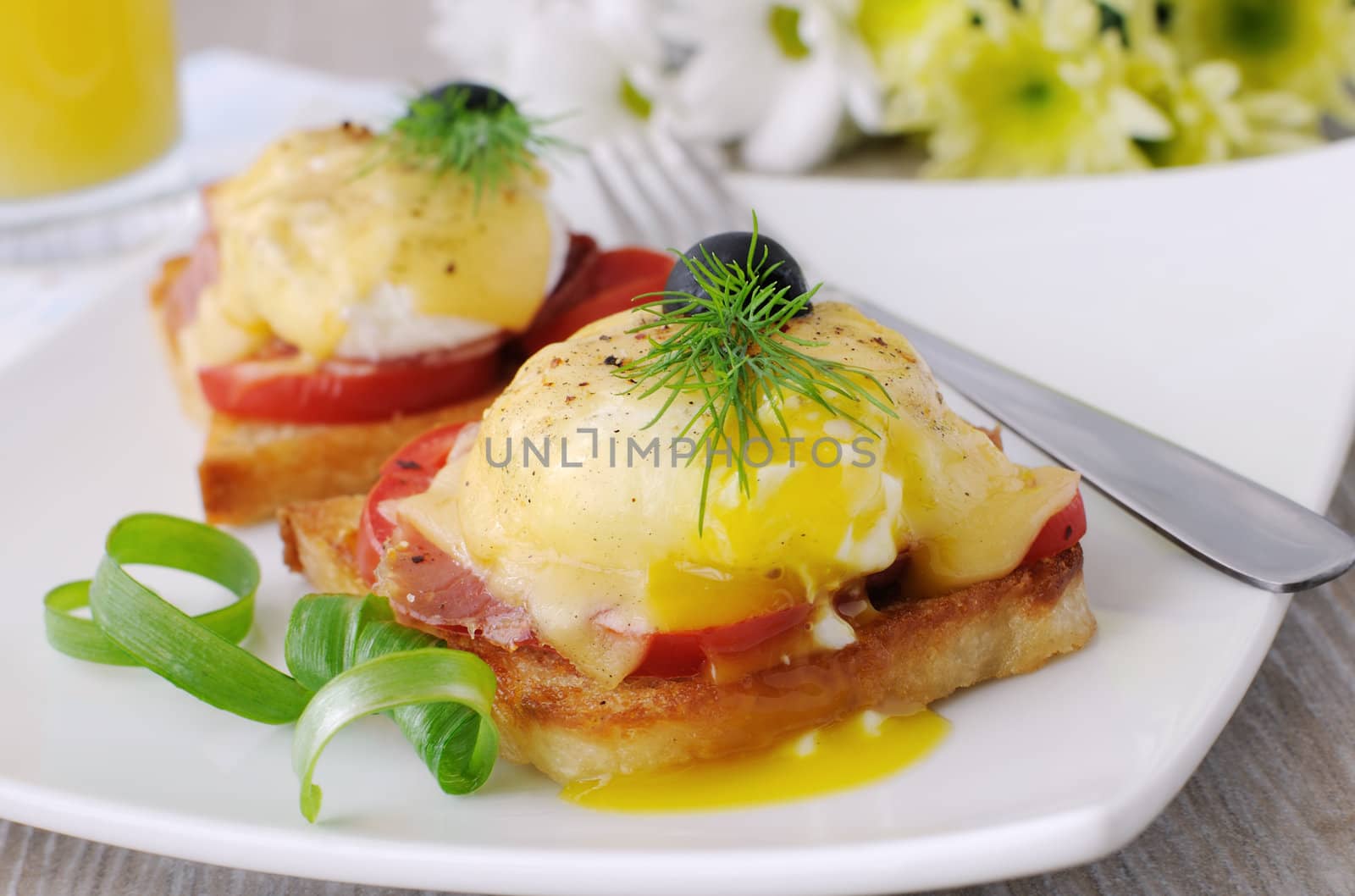 Eggs Benedict with ham and tomato on toast with cheese and orange juice

