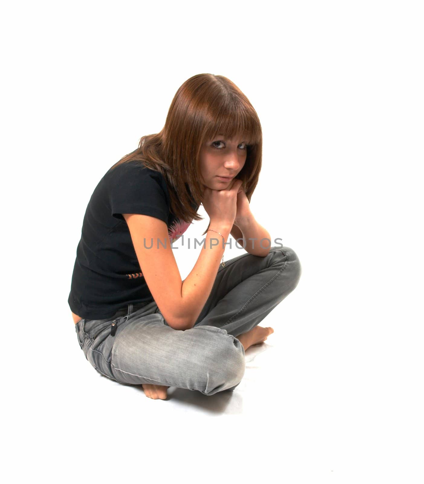 The girl in a black vest sits on a floor - a white background 