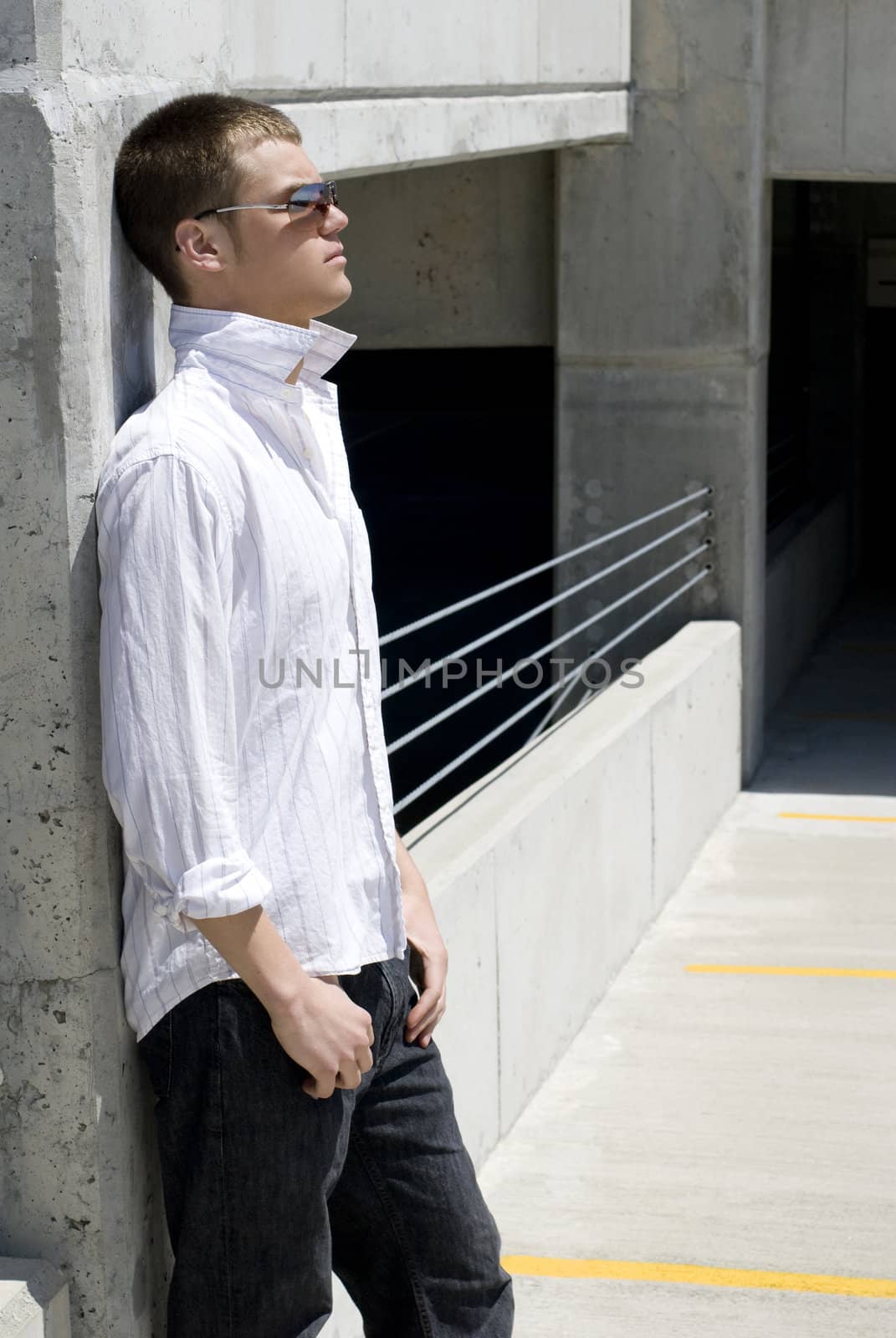 A young man outside against a wall.