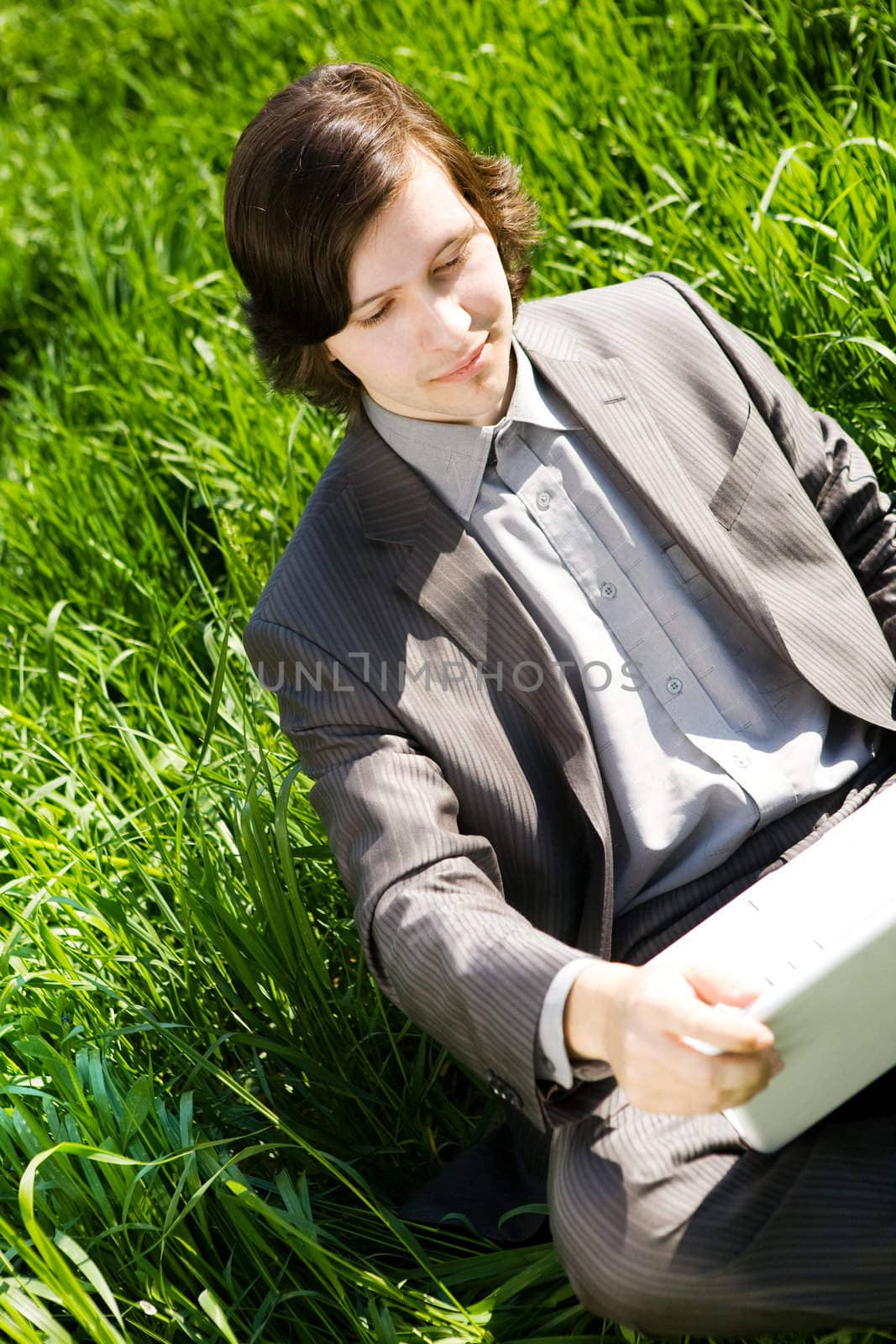 portrait of businessman with notebook on green grass field