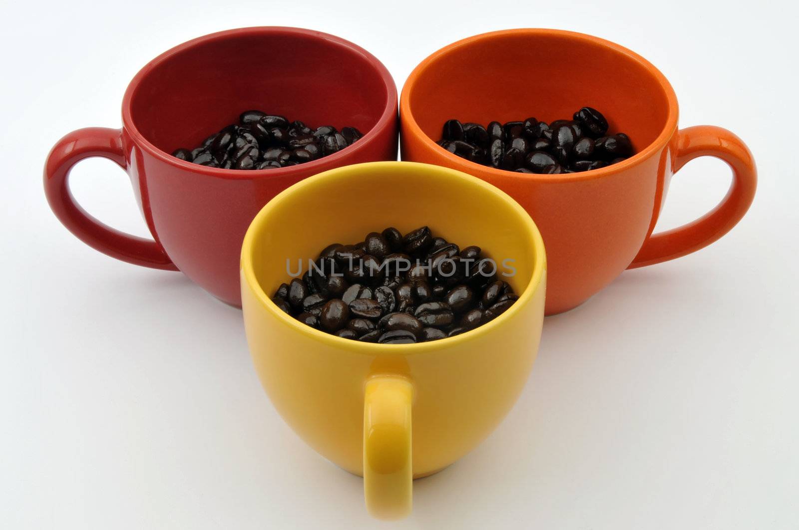 Three colorful cups full with coffe beans isolated on white