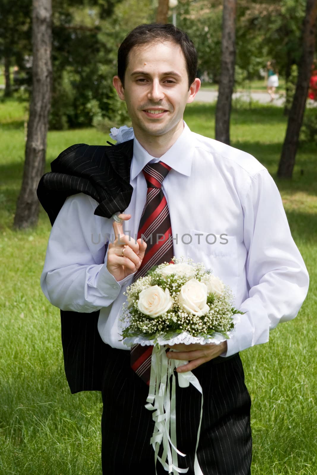 well-dressed groom with rose bouquet