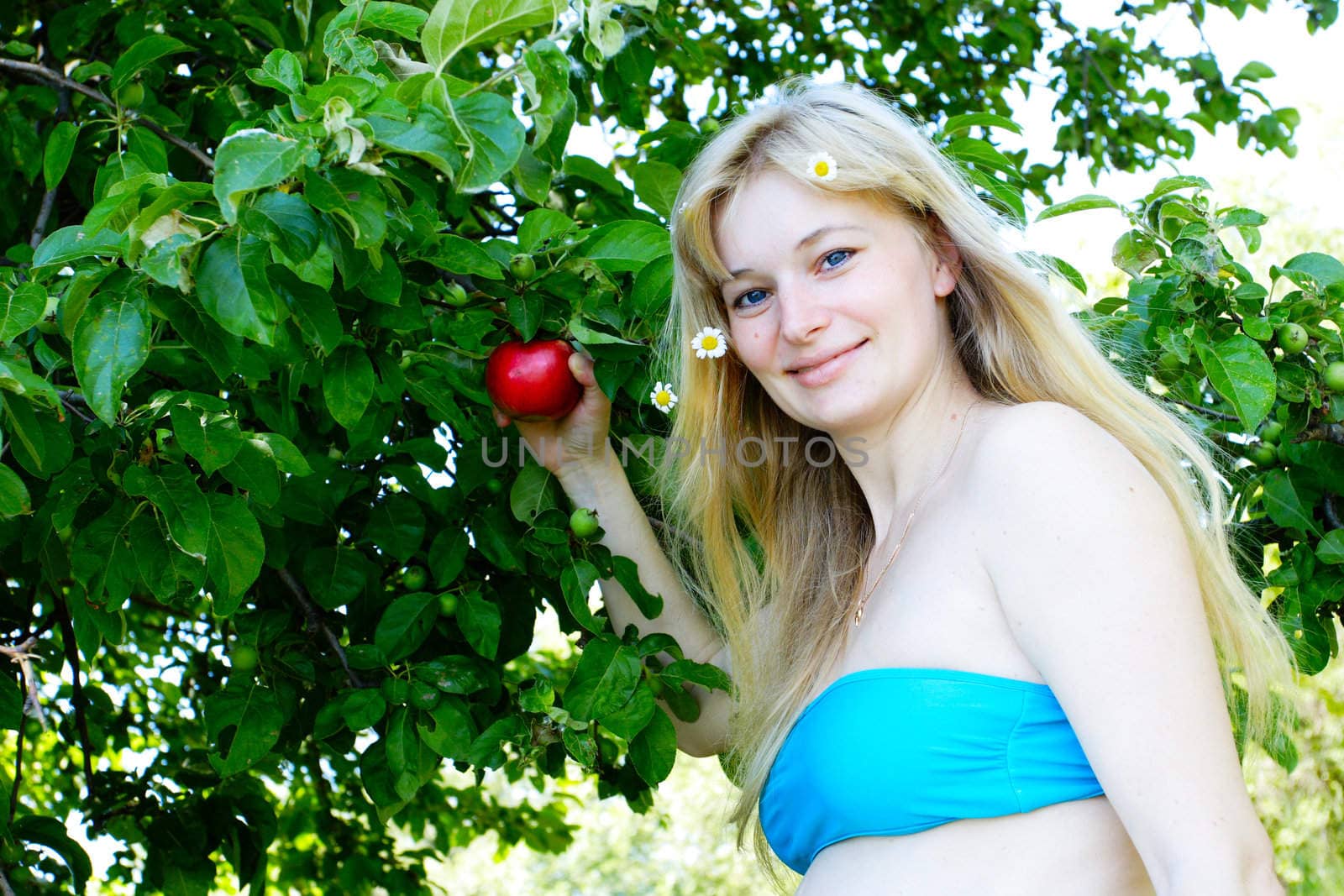 a pregnant woman with a red apple by the apple tree