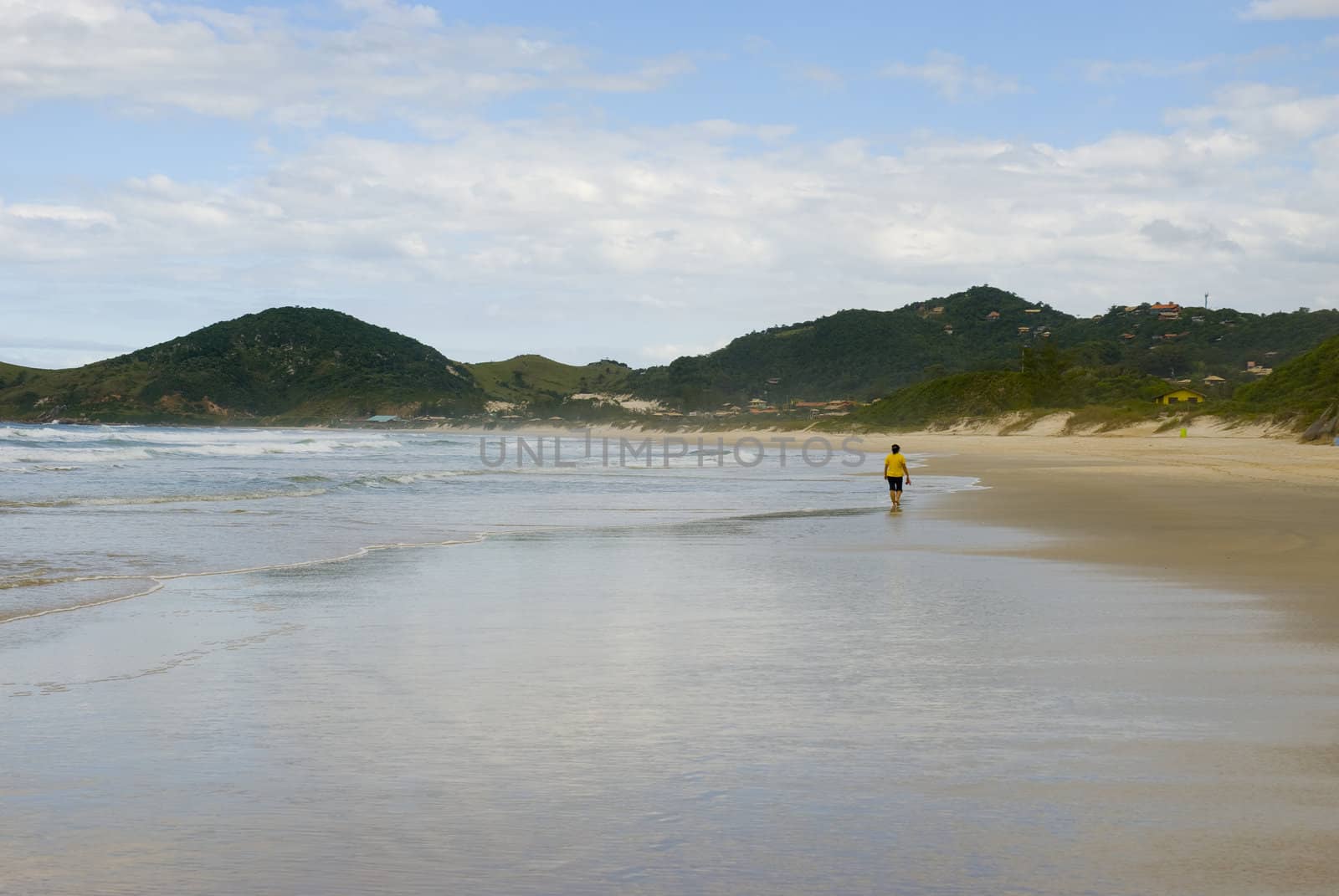 Woman walking alone on a deserted beach. Shot from behind.