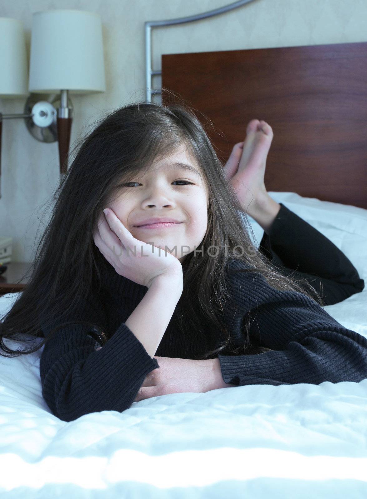 Six year old girl chin on hands thinking while lying down on bed