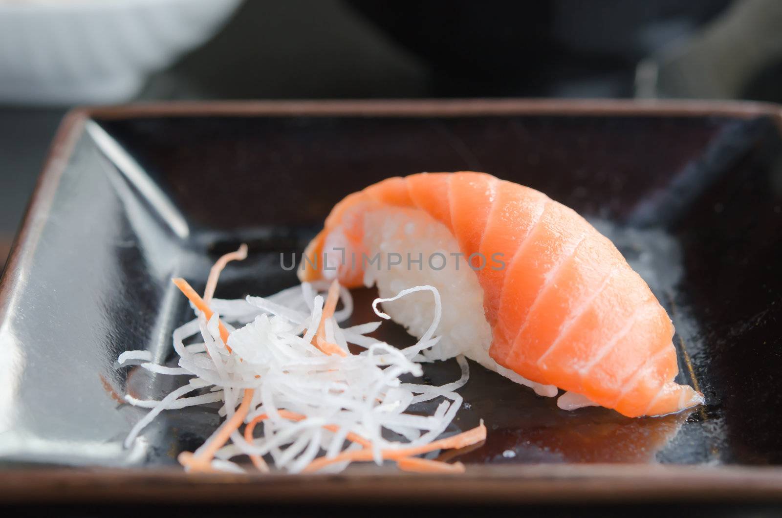 close up salmon sushi and slices daikon radishes