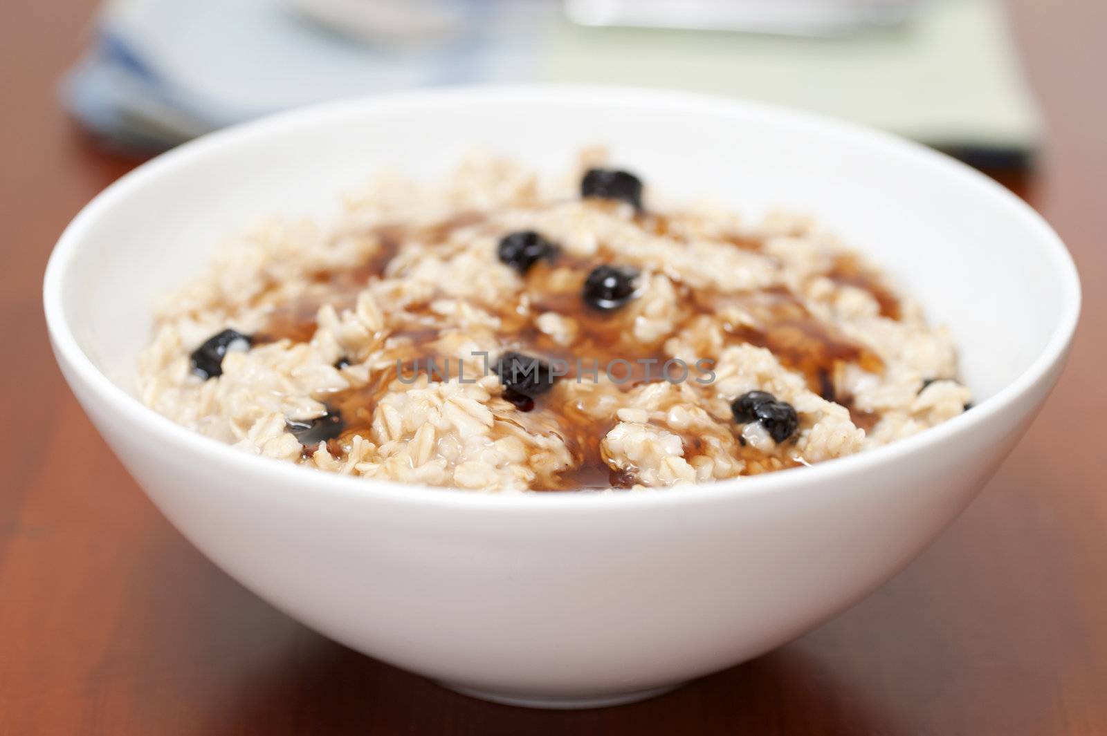 Bowl of oatmeal with raisins and maple syrup photographed closeup.