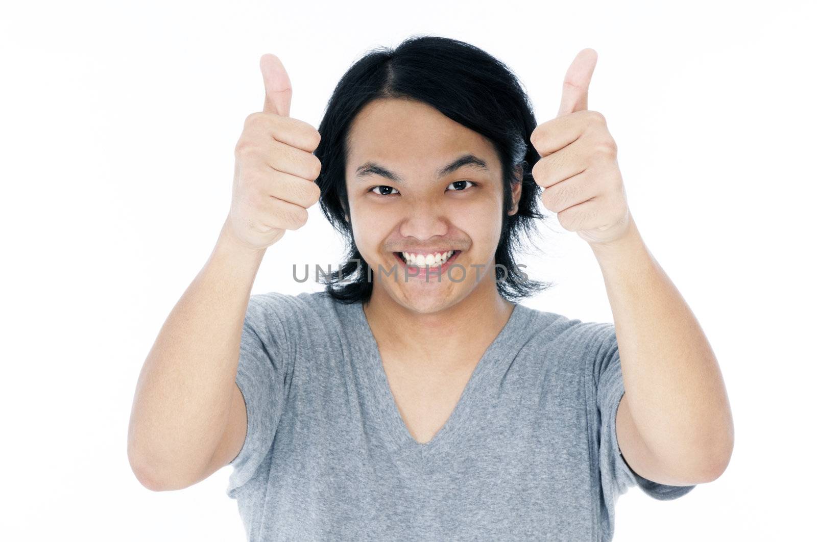 Portrait of a happy young Asian man giving thumbs up sign over white background.