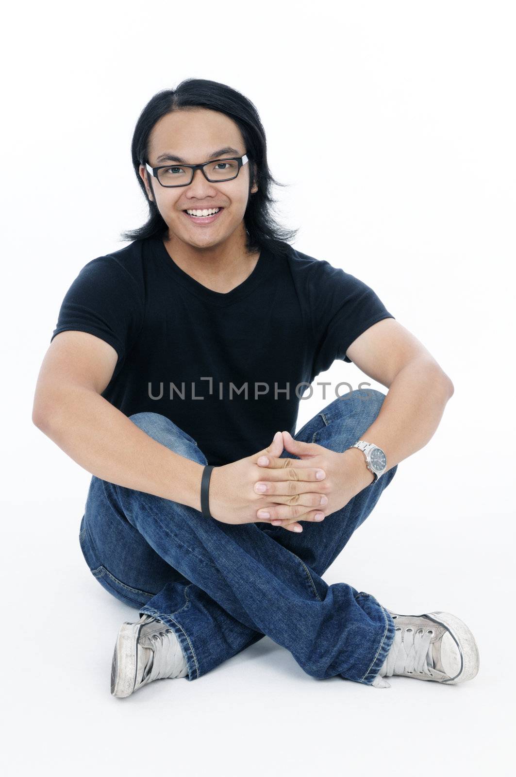 Happy young Asian man sitting relaxed on the  floor over white background.