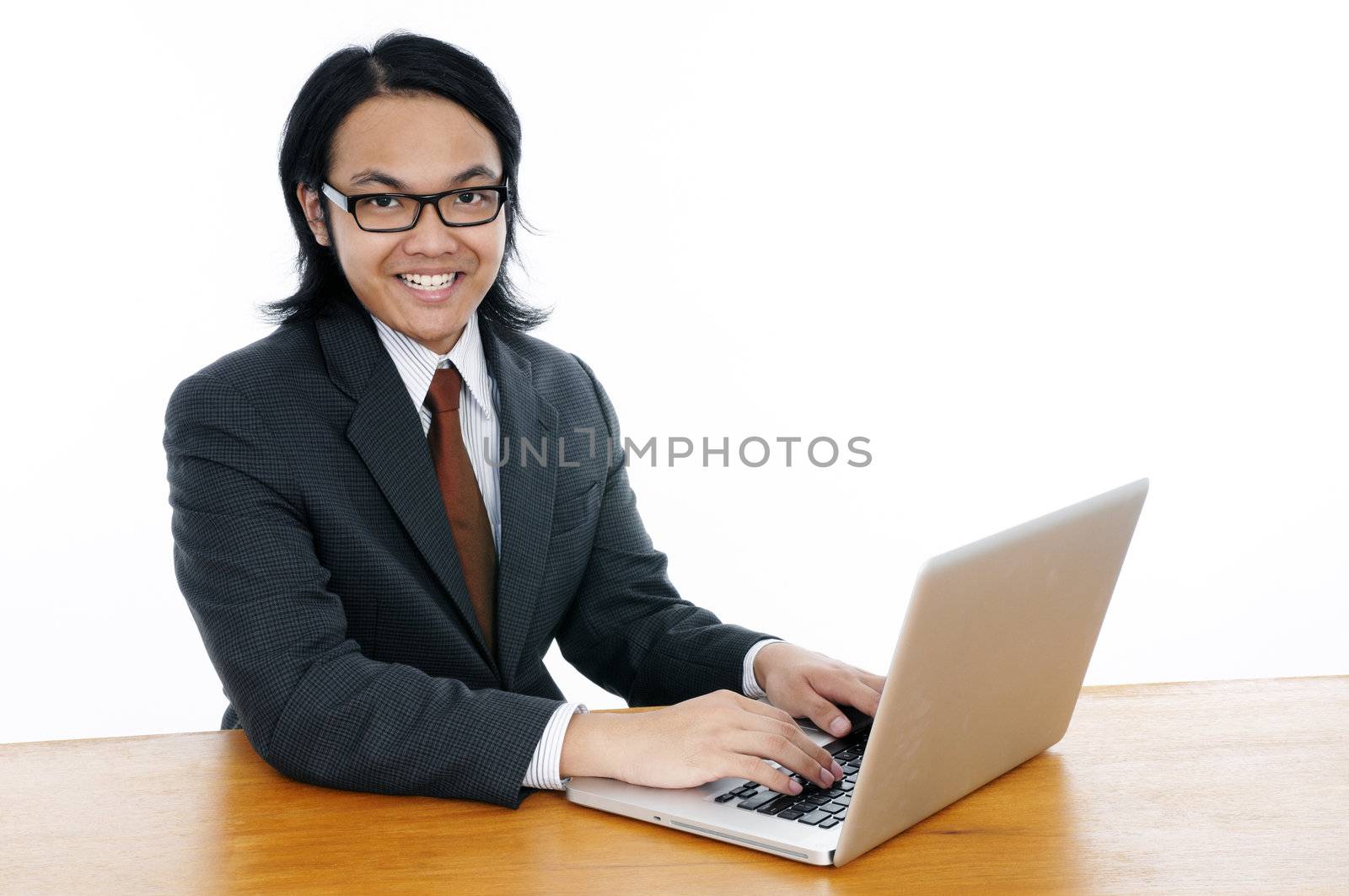 Portrait of a happy young Asian businessman using laptop over white background.