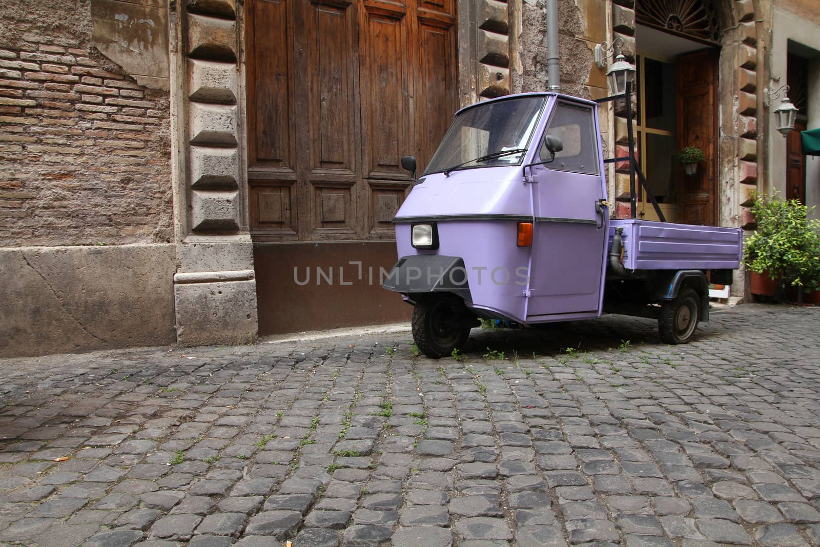 Rome, Italy. Cobblestone street and a funny three wheeled car.