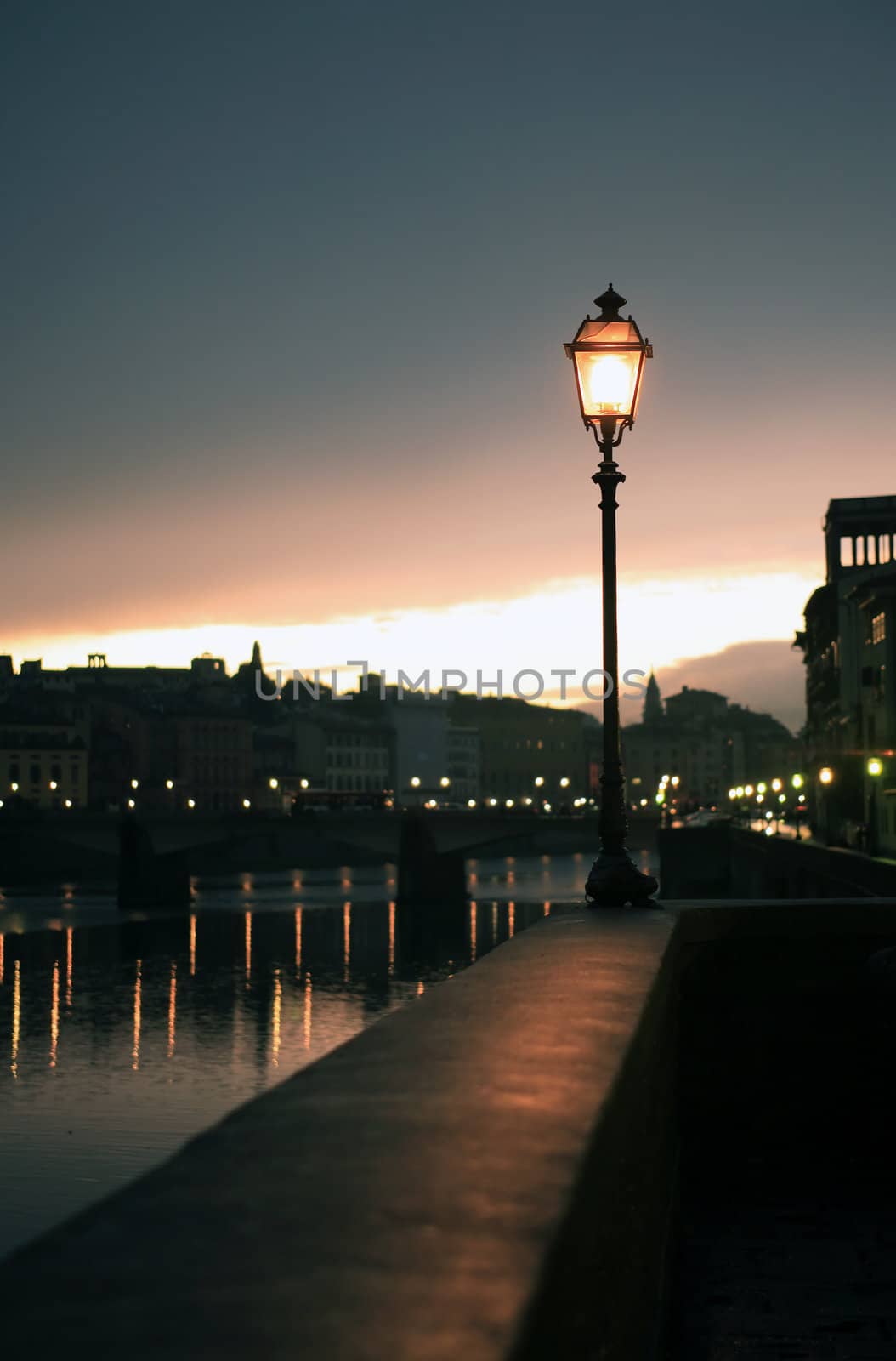 Night in Florence. Glowing vintage street lamp on background with Arno river