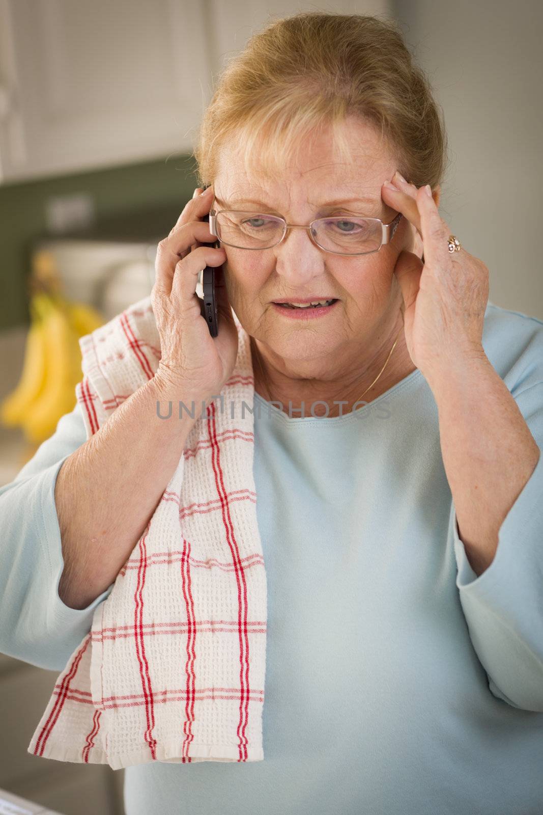 Shocked Senior Adult Woman on Her Cell Phone in Kitchen.