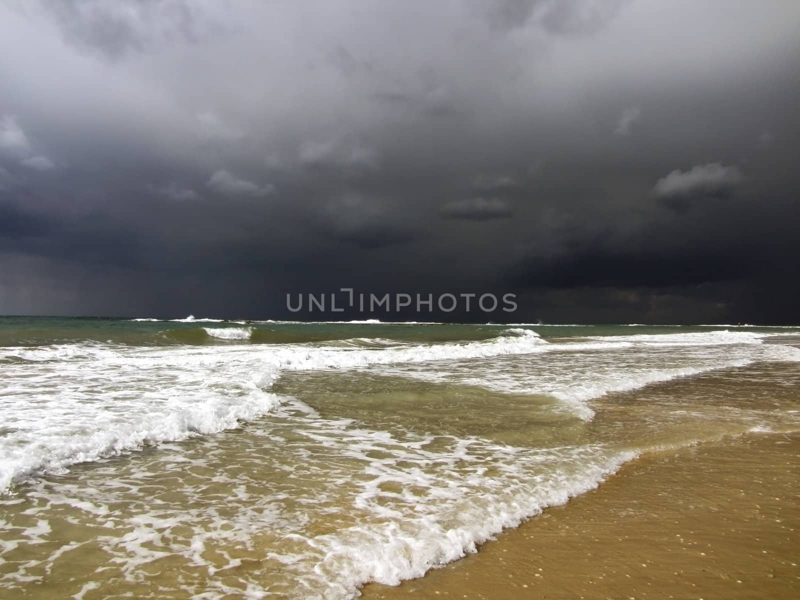 black storm clouds over the Mediterranean Sea and the waves incident on the beach