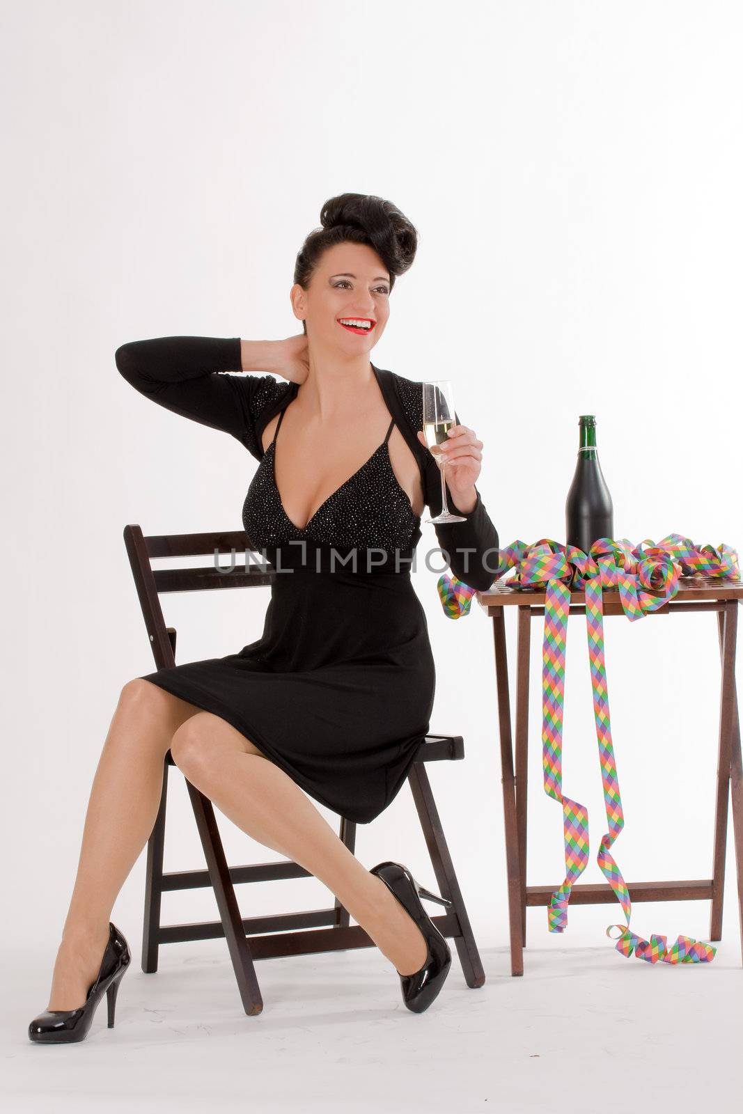 Woman with streamers and champagne sitting at the table when celebrating