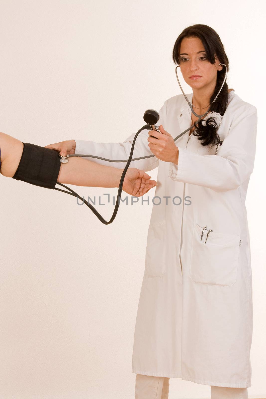 Physician measures the blood pressure at the arm of a patient