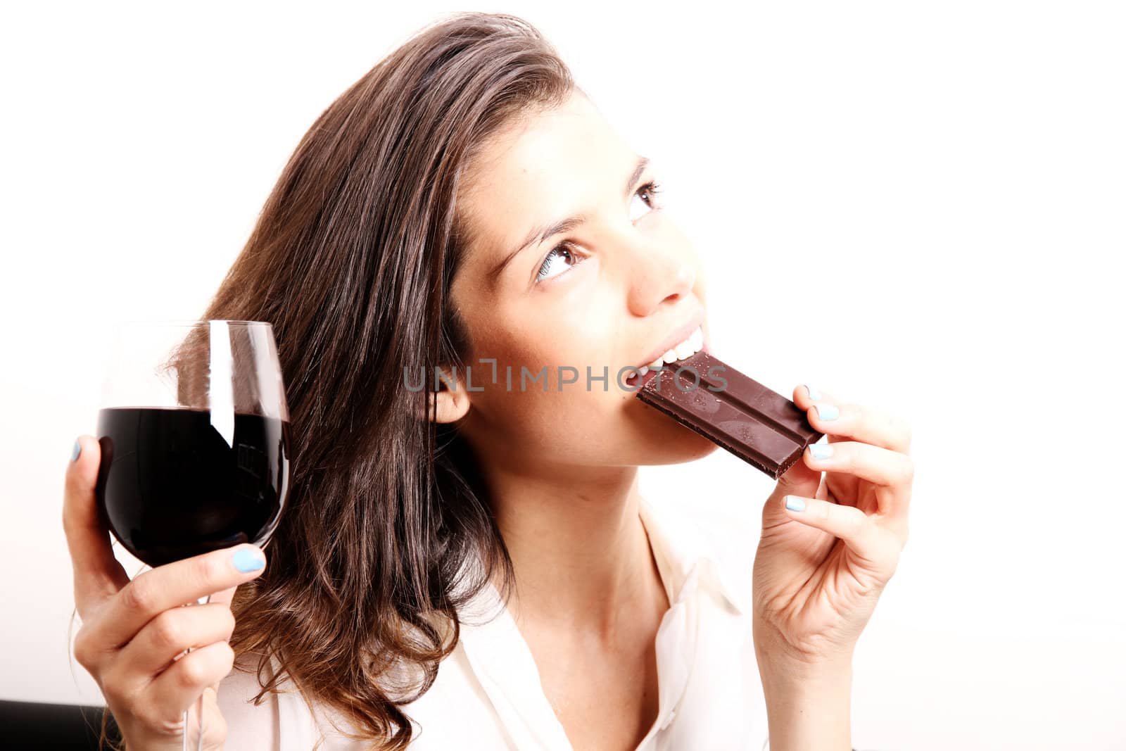 Portrait of a beautiful, latin Woman drinking red wine and eating chocolate.