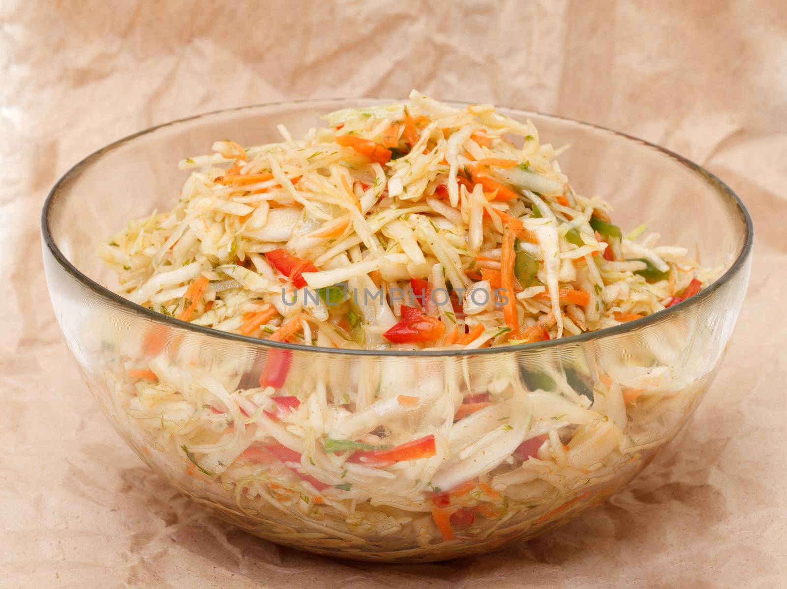 Coleslaw in glass bowl on brown crumpled recycled paper