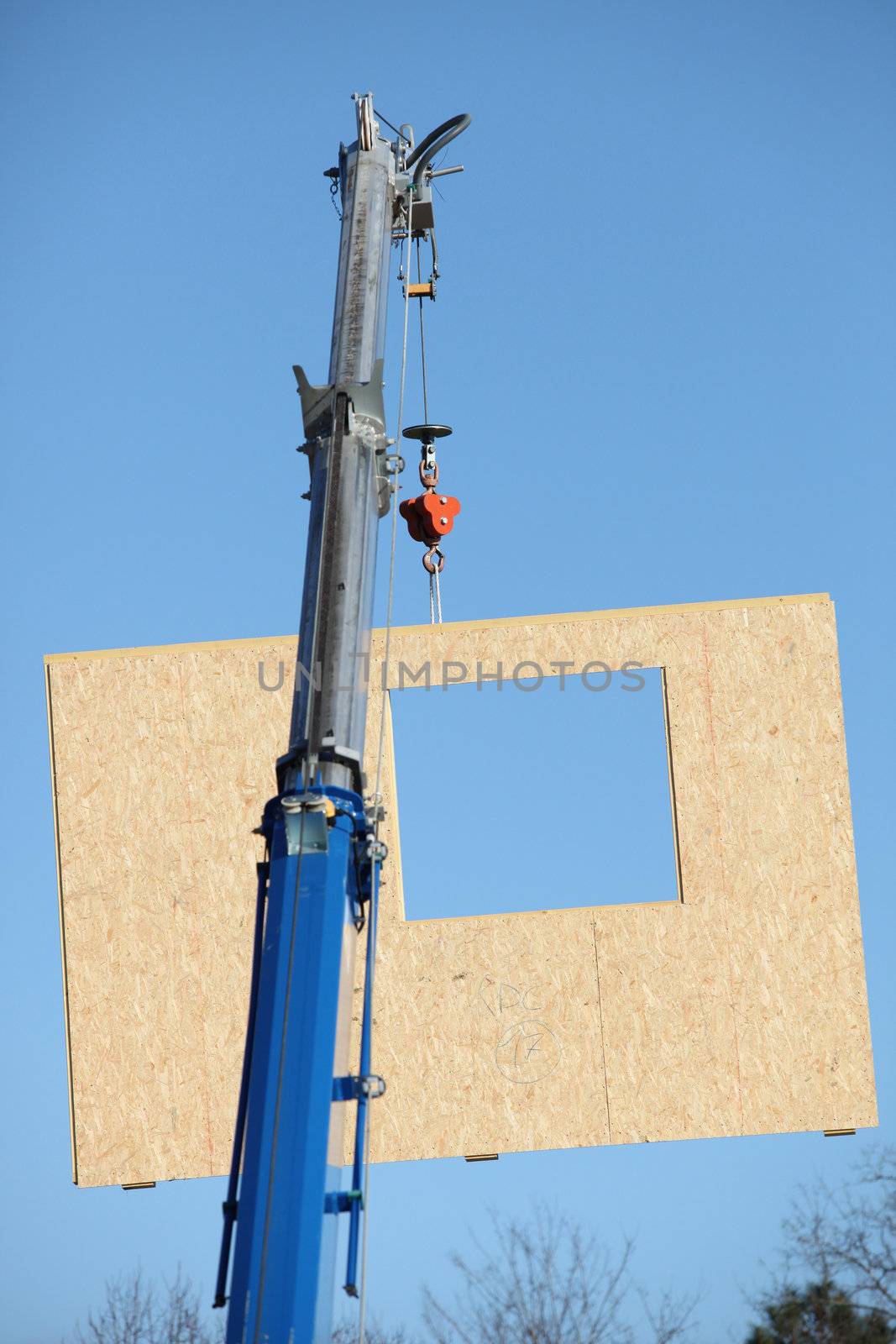 Crane lifting a section of wooden wall