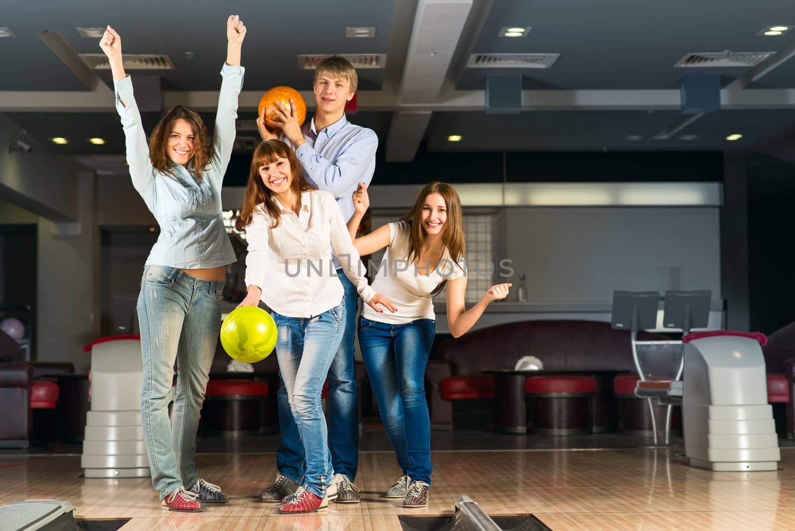 Group of young friends playing bowling, spending time with friends