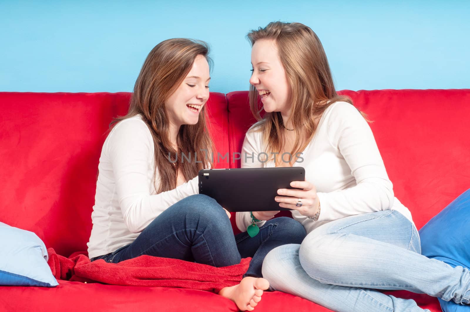 happy teenagers using tablet on the couch at homein the living room