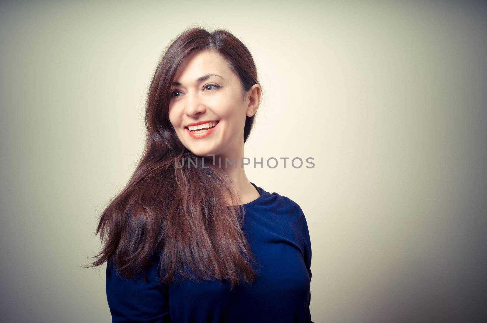 portrait of beautiful girl with long hair and blue sweater on gray background