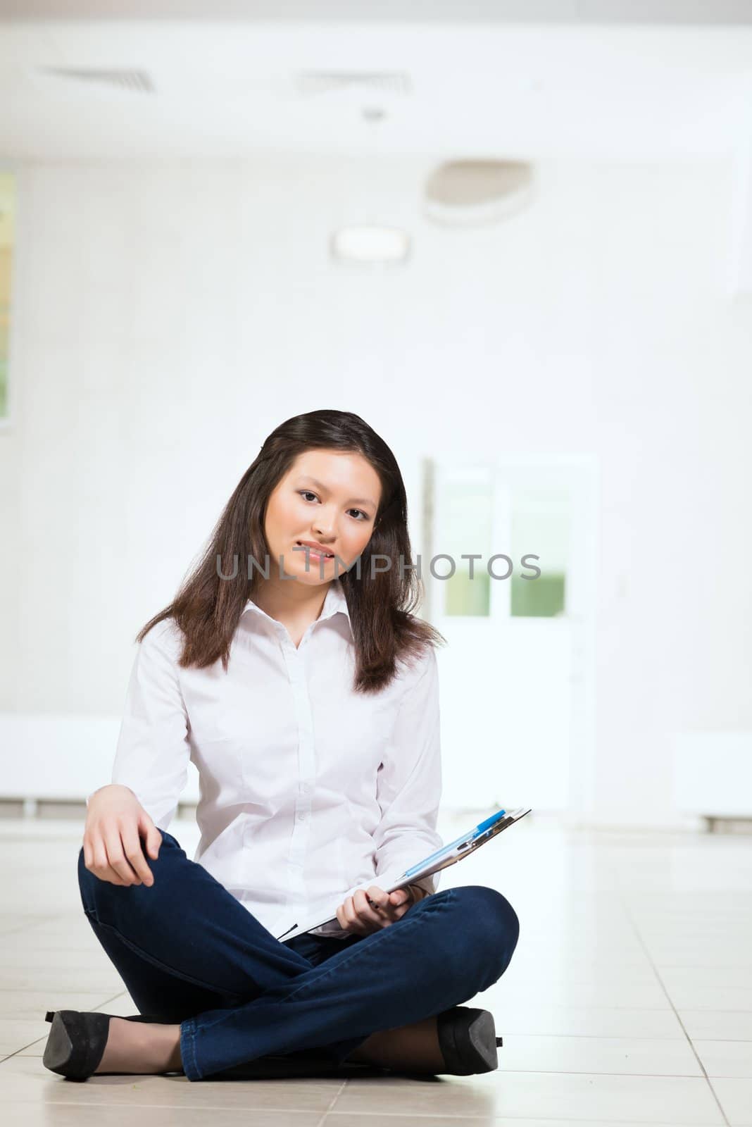 Portrait of an attractive woman sitting on the floor cross-legged and holds the tablet for notes