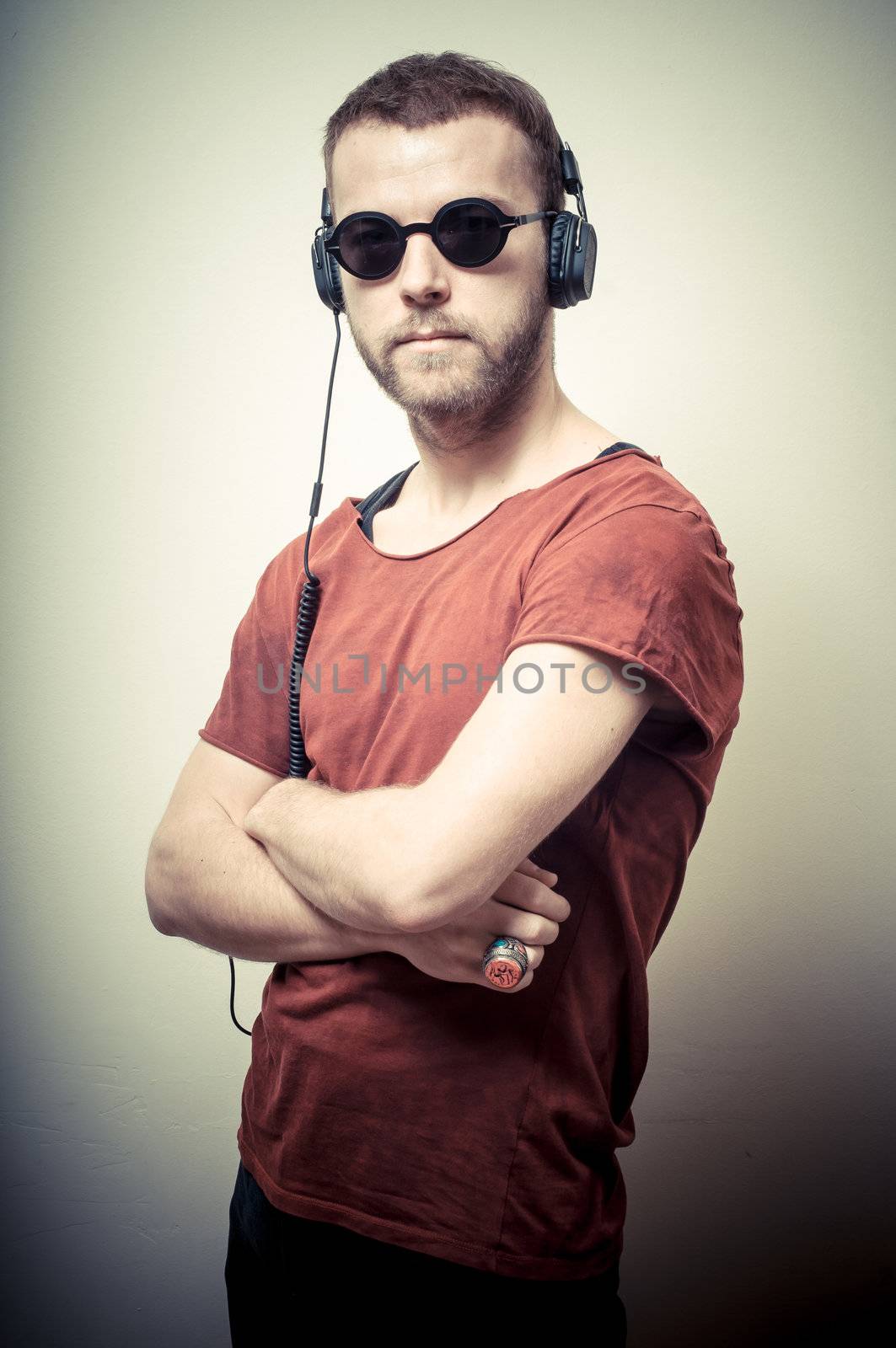 vintage portrait of fashion guy with headphones and sunglasses on gray background
