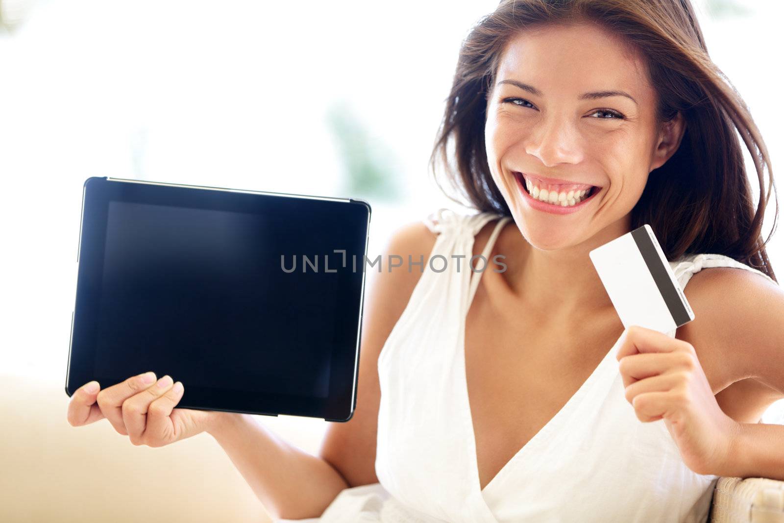 Internet shopping woman online with tablet pc and credit card. Internet shopper buying things on the internet showing blank tablet pc computer as sign. Multicultural Asian Caucasian model smiling happy