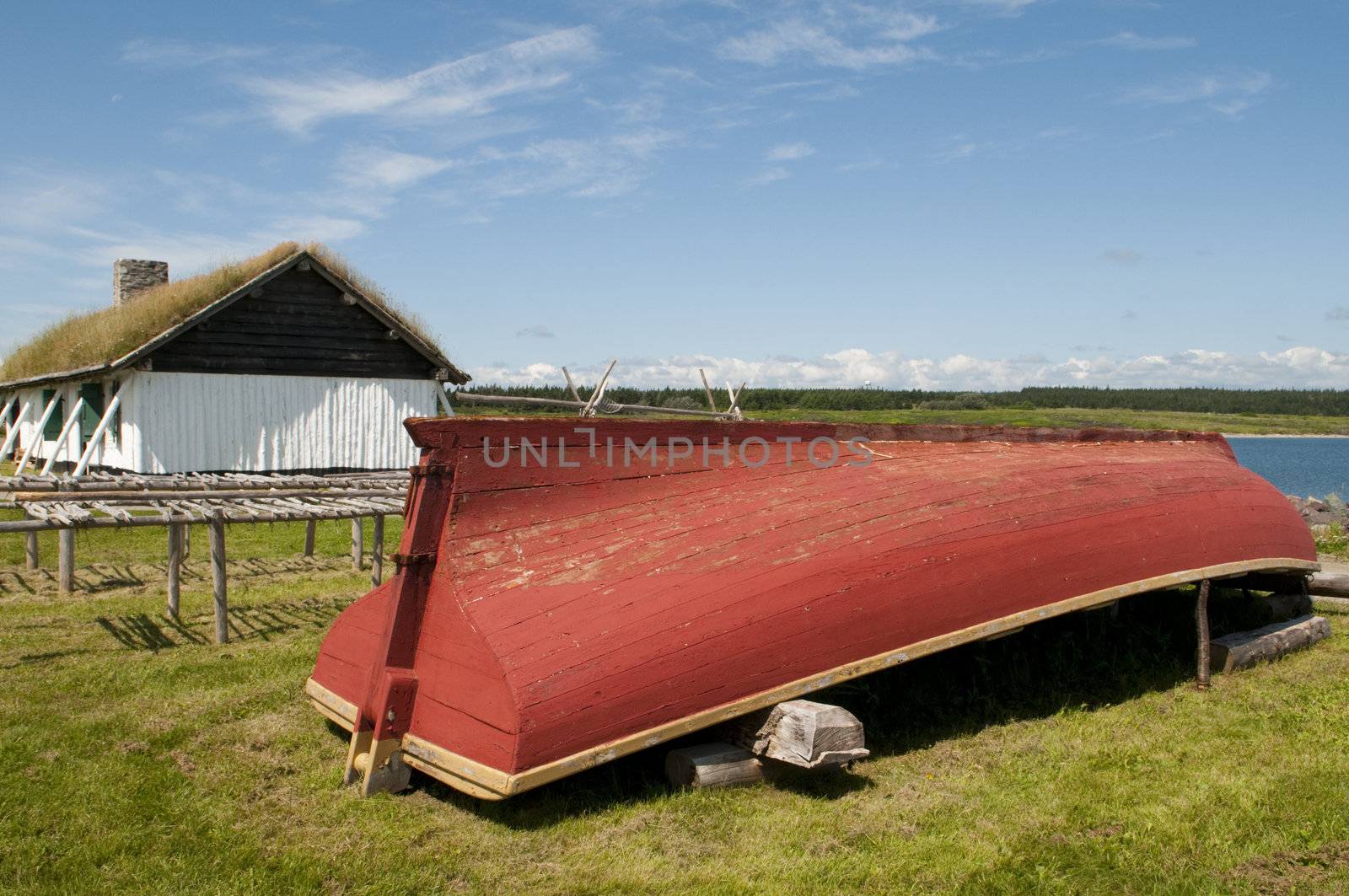 Vintage 18th century fishing boat with racks for drying fish and in the background the fisherman's home including a sod roof. 