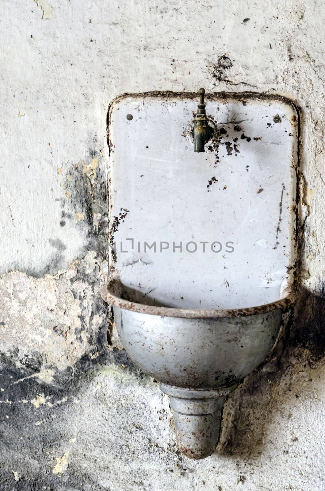 Old rusty metal sink mounted on a wall.