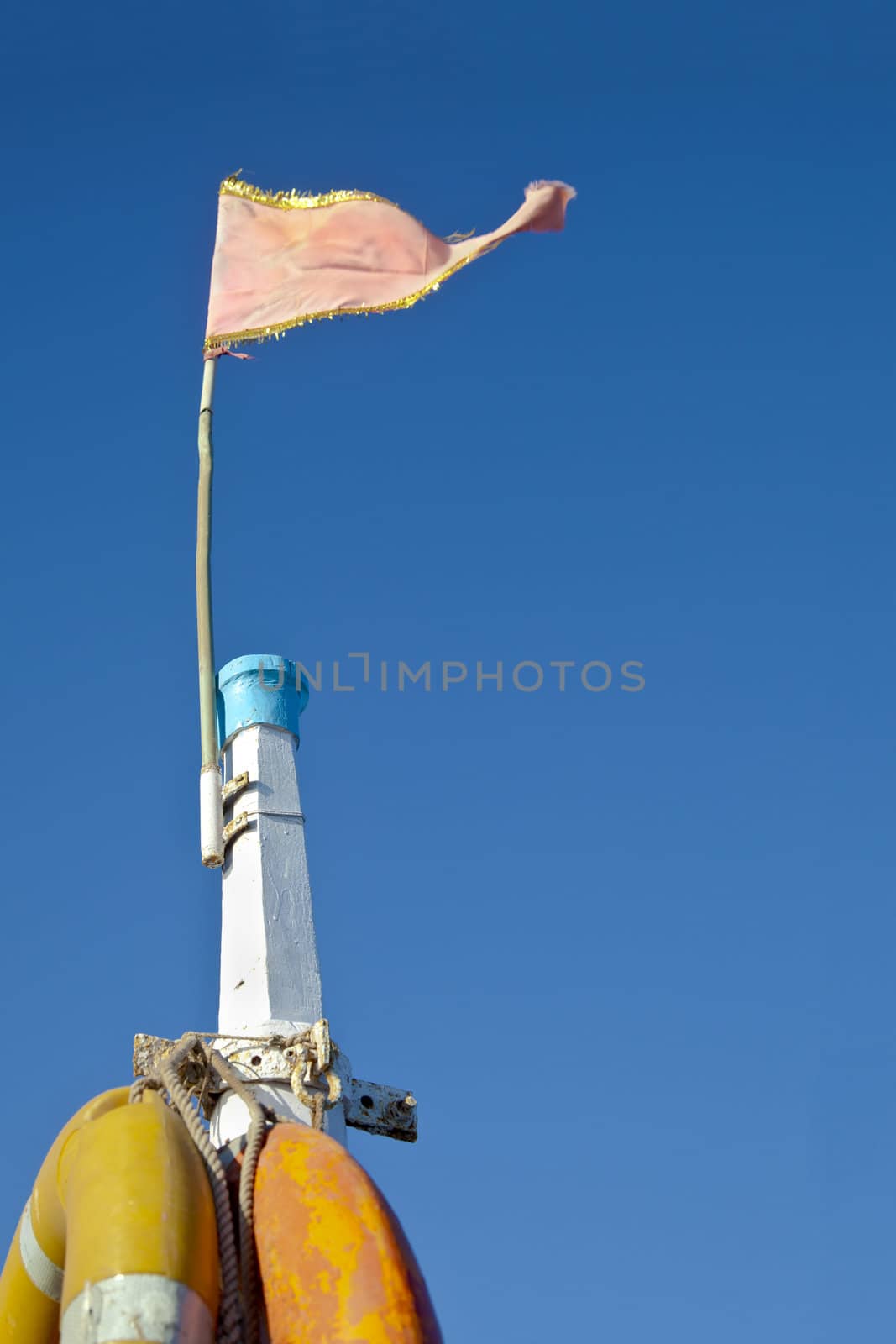 Dwarka Roadtrip. Concept of Rich blue sky split by a white mast bearing yellow life buoys and a pink frayed flag. Generic shot location Bet Dwarka, Gujarat, India