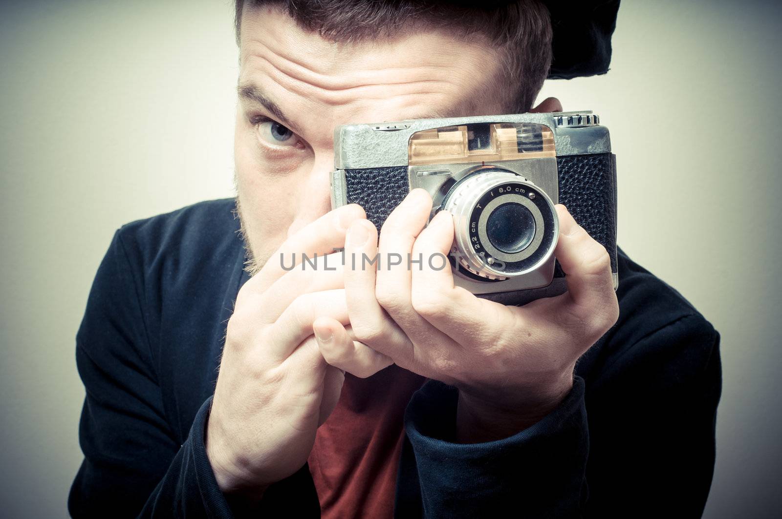vintage portrait of fashion guy with old camera on gray background