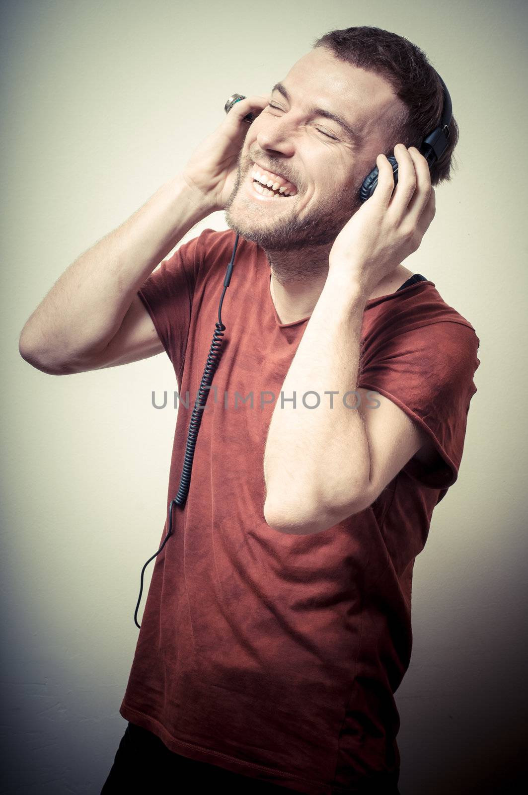vintage portrait of fashion smiling guy with headphones on gray background