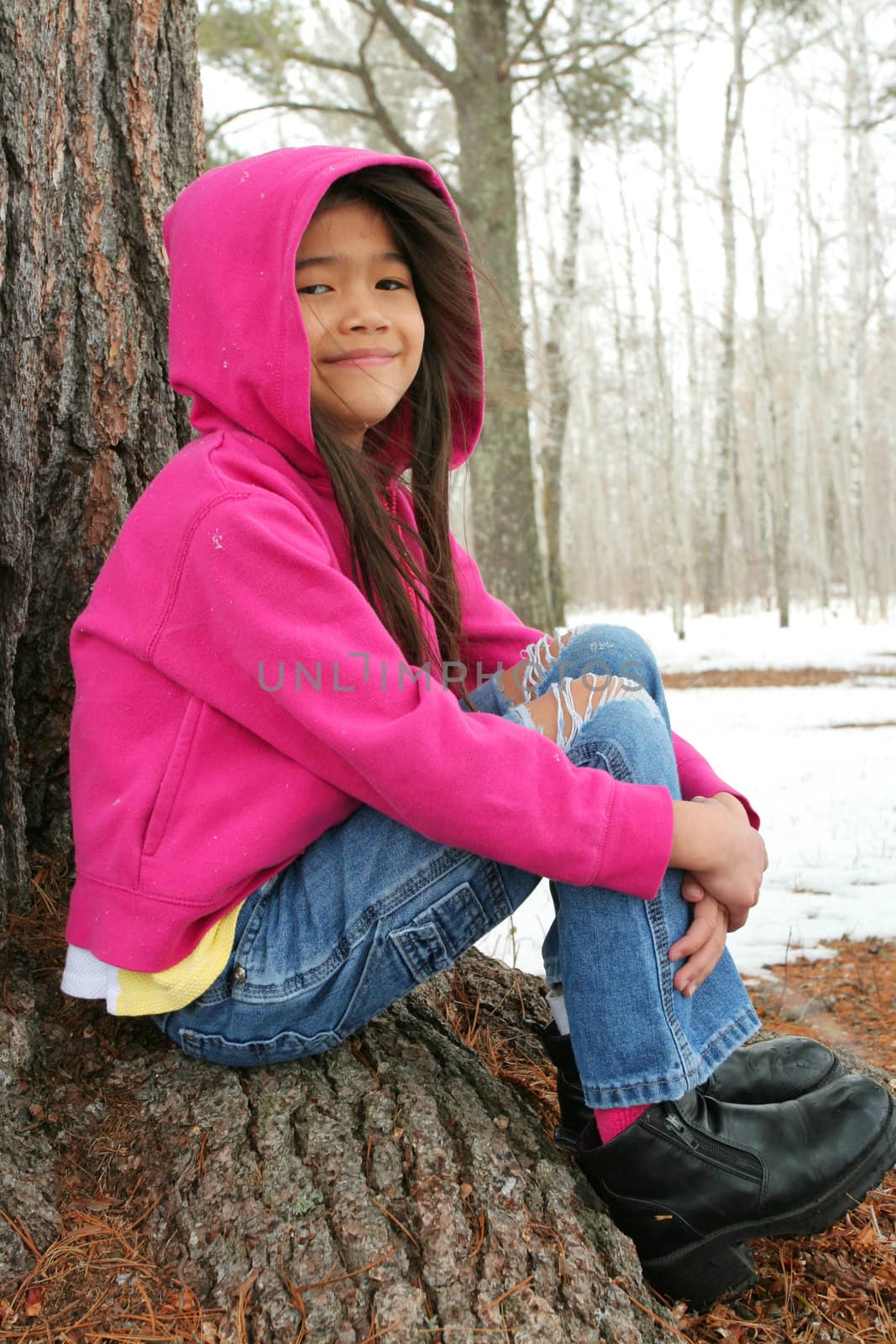 Child sitting under tree in winter