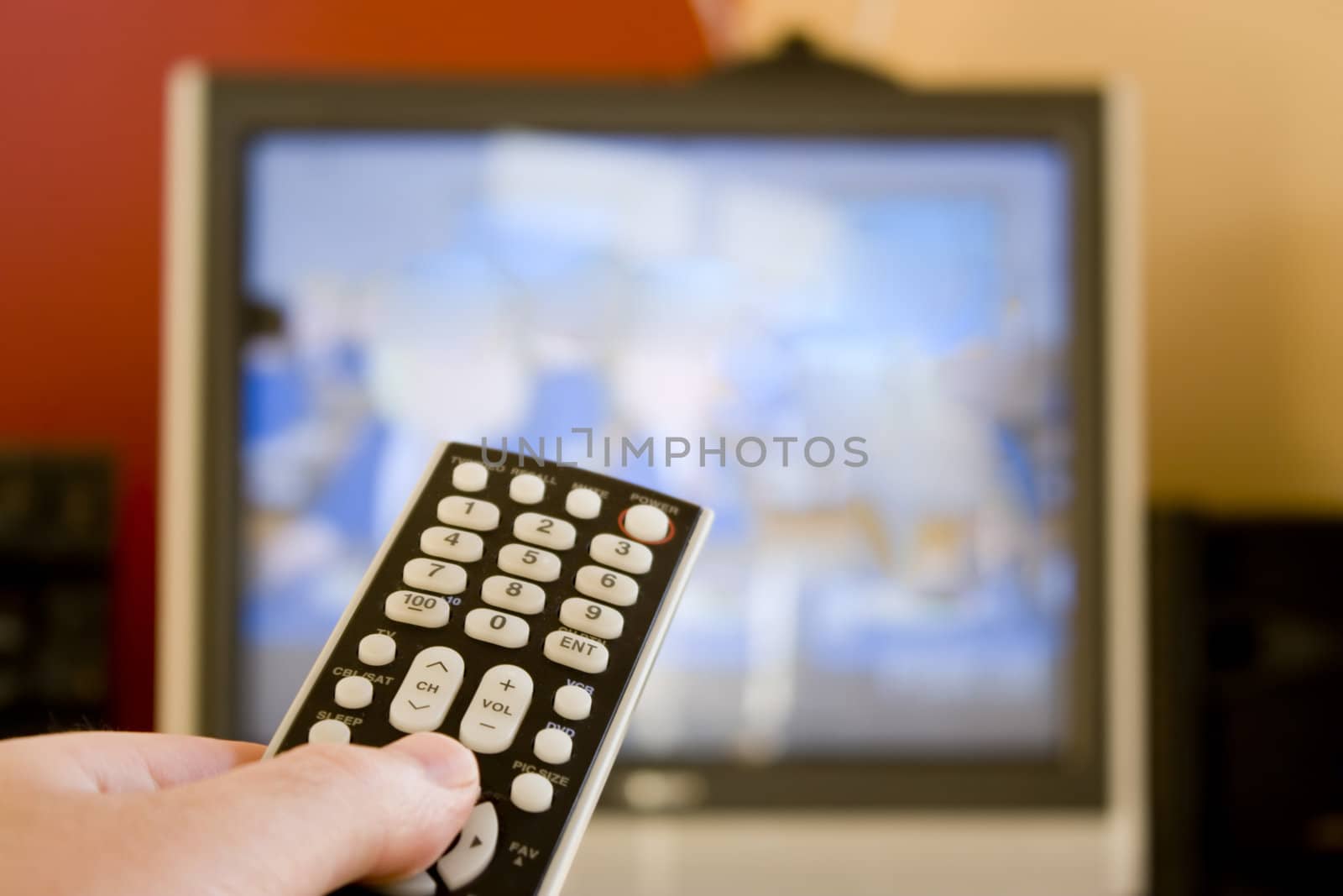 A remote control in hand.  Shallow depth of field, with focus on the remote.