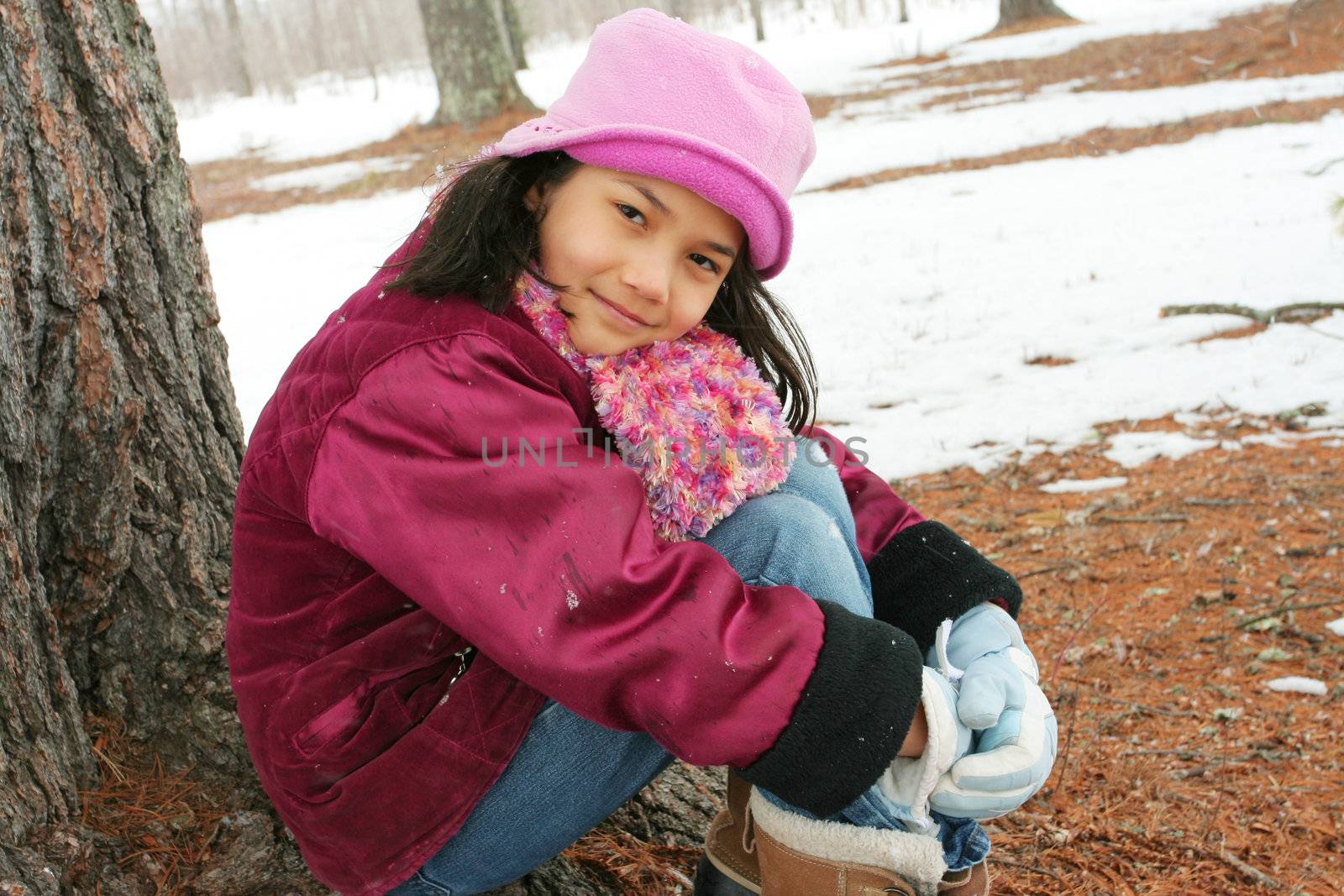 Nine year old girl enjoying sitting under tree in winter