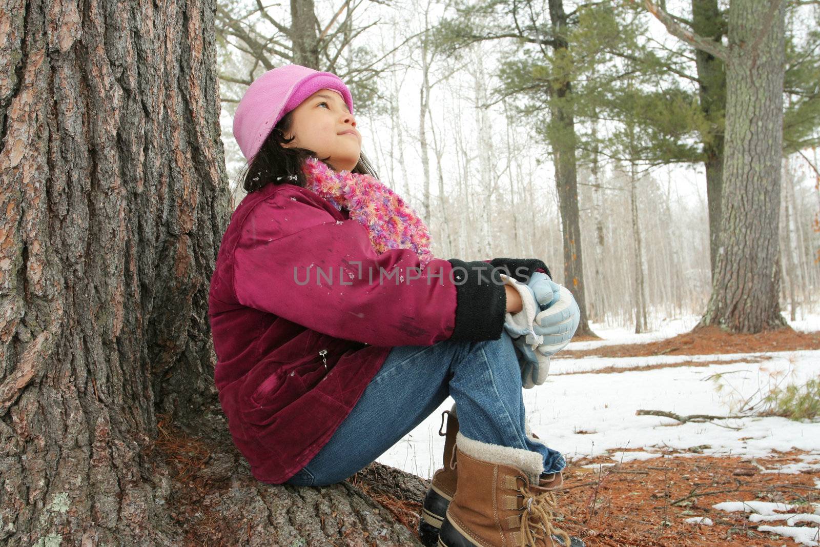 Nine year old girl enjoying sitting under tree in winter